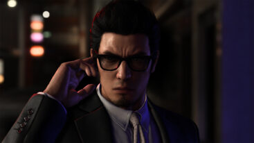 Kiryu holds his hand up to his hear while he looks sternly forward in sunglasses