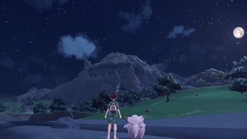 A pokemon trainer stands next to their Clefairy as they look toward a large mountain and a night sky