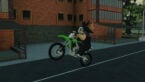 Roblox Ride Storm A Silver Helmeted Avatar Is Performing A Wheelie On A Green Dirtbike On A Pavement With A Red Brick Building In The Background